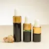 Drie flesjes etherische zeewierolie van 2 ml, 3 ml en 4 ml naast een zeeschelp