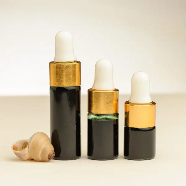 Drie flesjes etherische zeewierolie van 2 ml, 3 ml en 4 ml naast een zeeschelp
