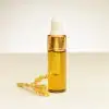 4 ml flesje etherische mimosa-olie naast een mimosa bloesem
